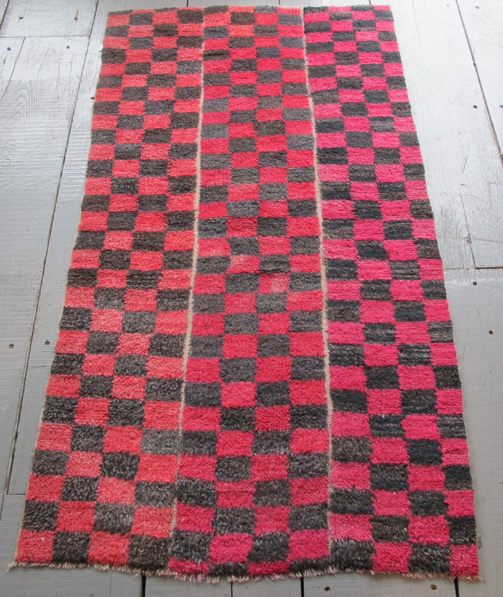 An antique Tibetan wool meditation rug featuring a three-panel chequerboard pattern in pink and dark grey. View IX