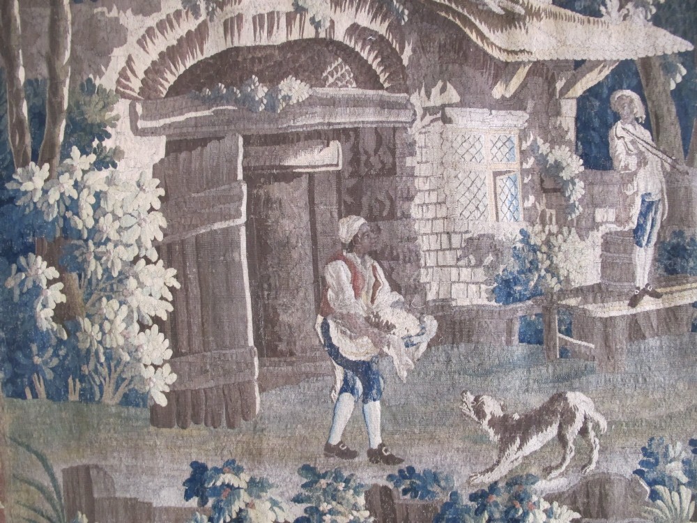 A large late 18th-century French woven tapestry portraying a pastoral scene with dancing figures, a stone building, and leafy trees enclosed within a decorative floral border. View IV