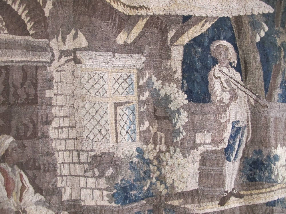 A large late 18th-century French woven tapestry portraying a pastoral scene with dancing figures, a stone building, and leafy trees enclosed within a decorative floral border. View V