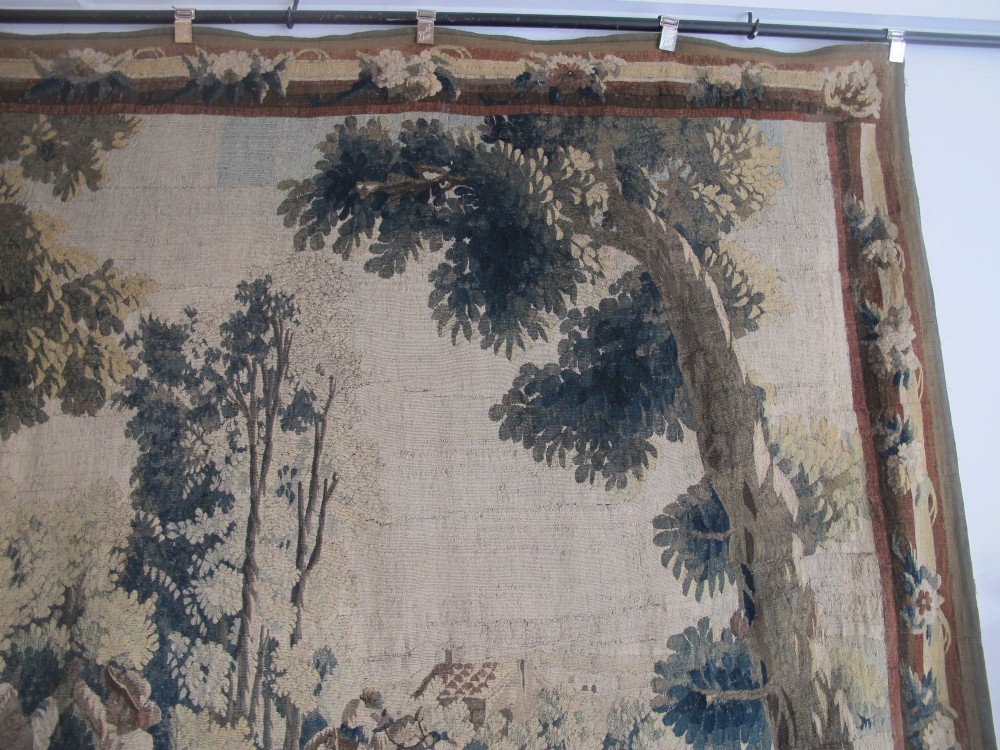 A large late 18th-century French woven tapestry portraying a pastoral scene with dancing figures, a stone building, and leafy trees enclosed within a decorative floral border. View IX