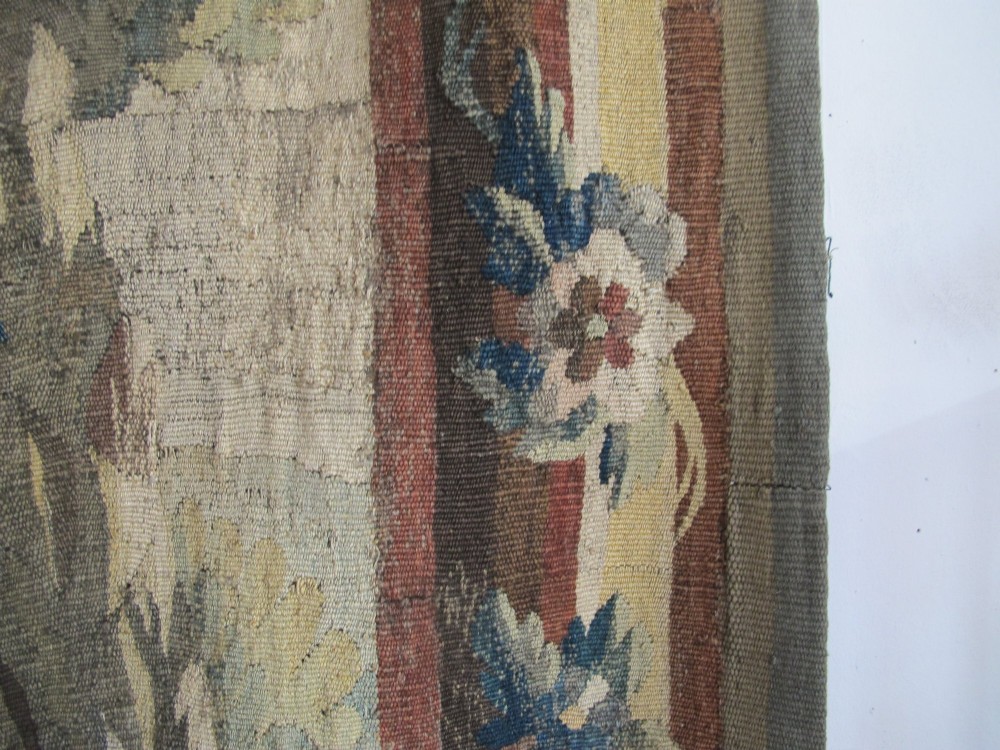 A large late 18th-century French woven tapestry portraying a pastoral scene with dancing figures, a stone building, and leafy trees enclosed within a decorative floral border. View XIII