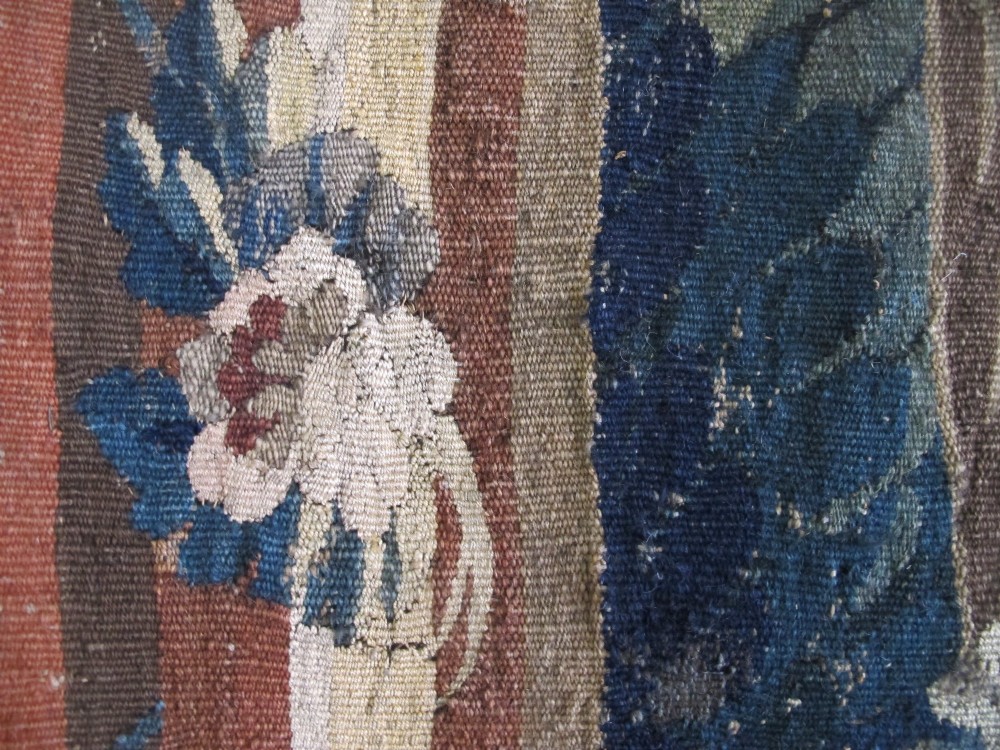 A large late 18th-century French woven tapestry portraying a pastoral scene with dancing figures, a stone building, and leafy trees enclosed within a decorative floral border. View XIV