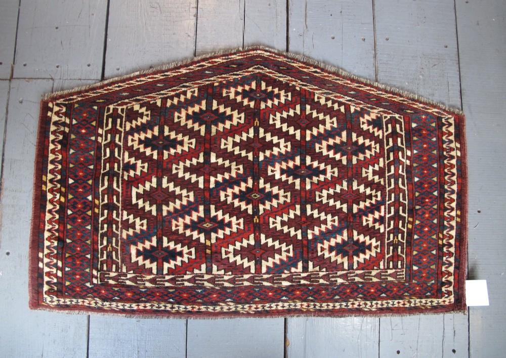 A pentagonal hand-woven wool textile featuring a red and cream geometric diamond lattice pattern with dark navy blue accents.