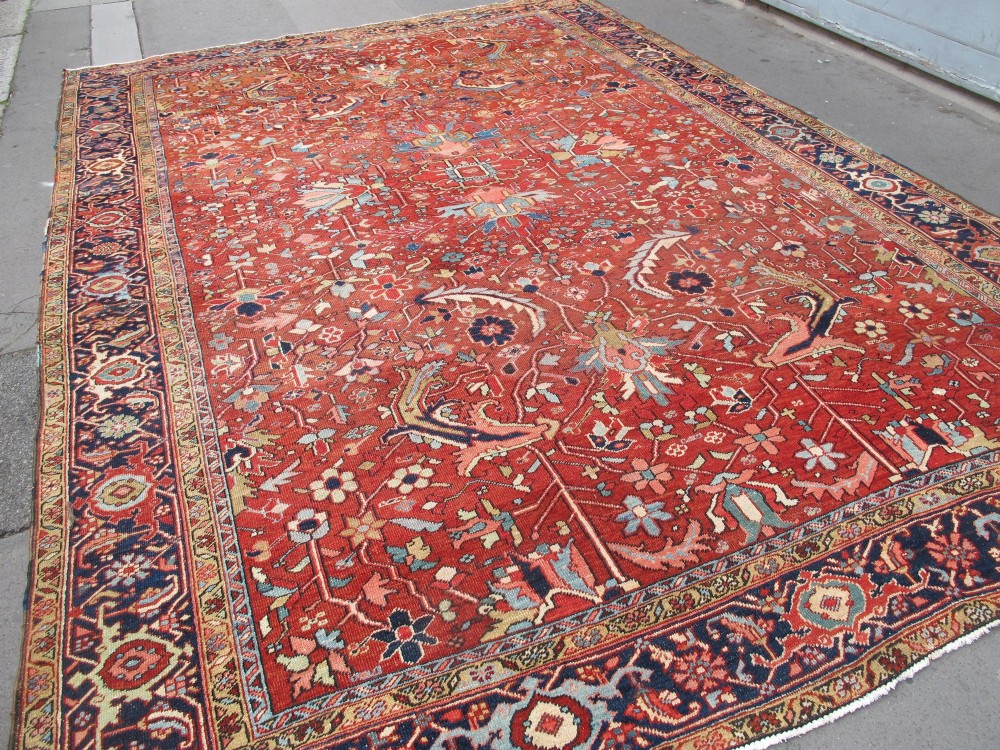 A large late 19th-century Heriz wool carpet featuring an all-over geometric floral motif in terracotta red and navy blue shades. View II