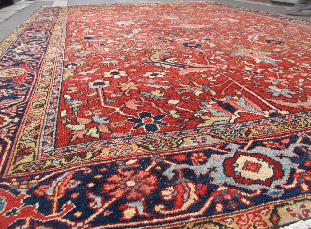 A large late 19th-century Heriz wool carpet featuring an all-over geometric floral motif in terracotta red and navy blue shades. View III