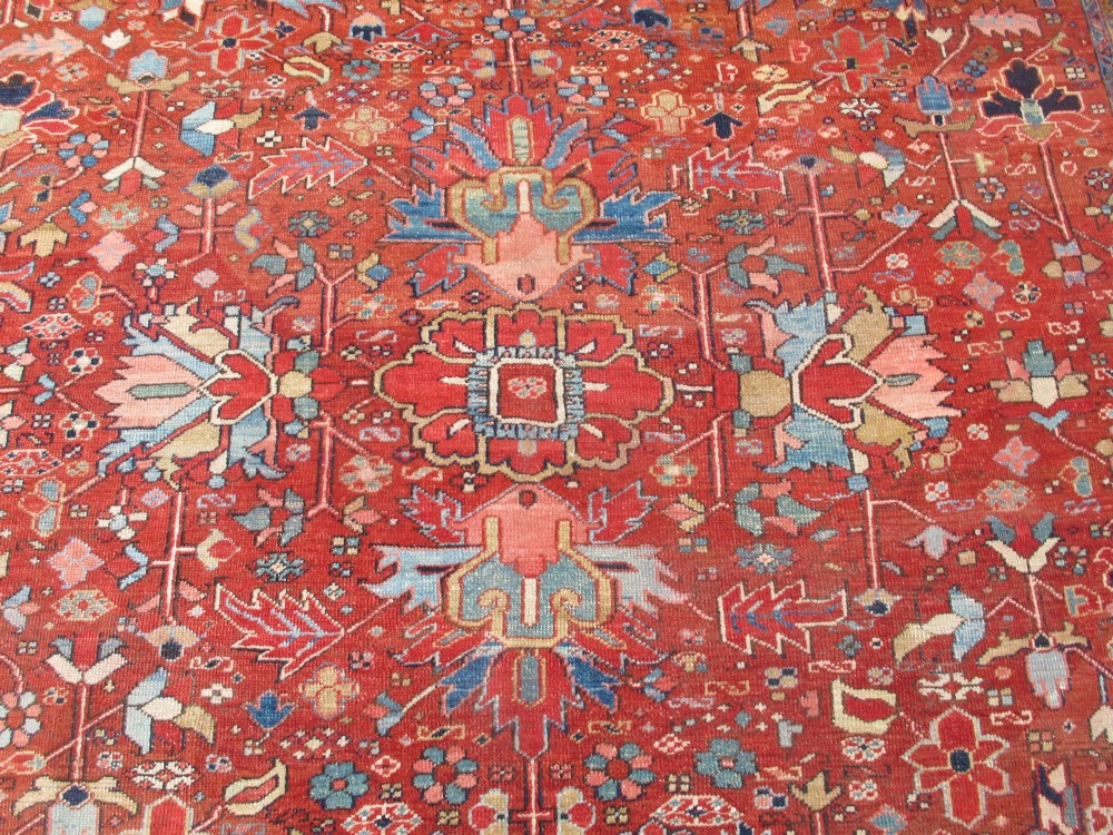 A large late 19th-century Heriz wool carpet featuring an all-over geometric floral motif in terracotta red and navy blue shades. View IV