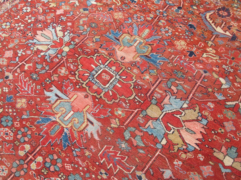 A large late 19th-century Heriz wool carpet featuring an all-over geometric floral motif in terracotta red and navy blue shades. View V