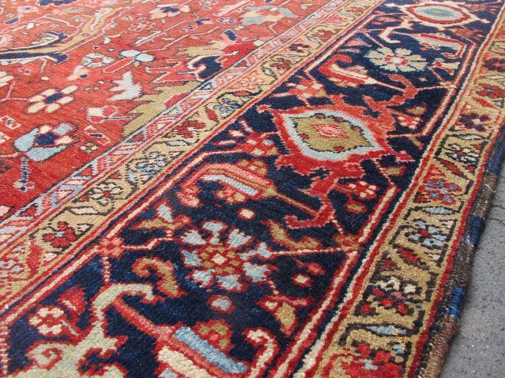 A large late 19th-century Heriz wool carpet featuring an all-over geometric floral motif in terracotta red and navy blue shades. View VII