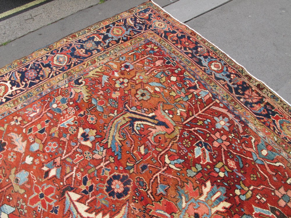 A large late 19th-century Heriz wool carpet featuring an all-over geometric floral motif in terracotta red and navy blue shades. View XI