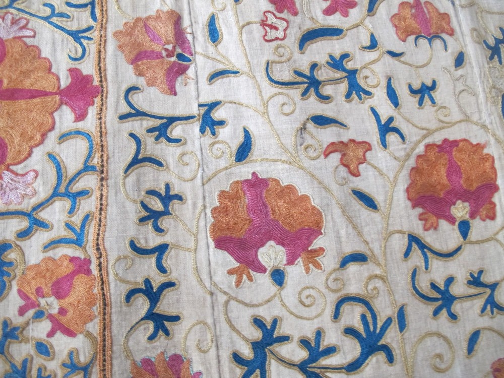 A rectangular hand-embroidered cream cotton textile decorated with orange, pink, and green silk floral roundels and scrolling vine borders. View XI