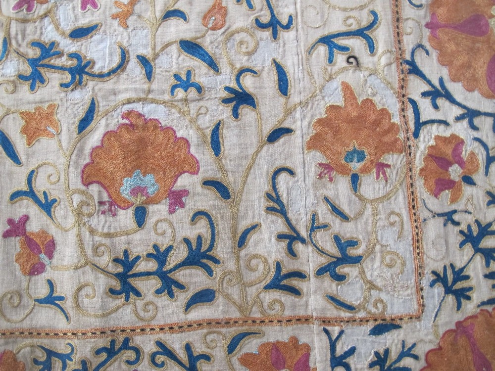 A rectangular hand-embroidered cream cotton textile decorated with orange, pink, and green silk floral roundels and scrolling vine borders. View XII