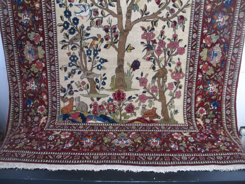An antique hand-knotted Persian Isfahan wool rug featuring a central cream field with a detailed Tree of Life and bird motifs, framed by a wide deep red floral border. View II