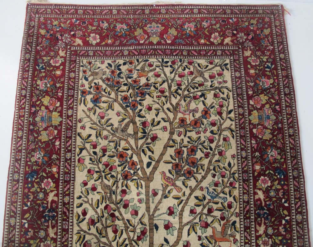 An antique hand-knotted Persian Isfahan wool rug featuring a central cream field with a detailed Tree of Life and bird motifs, framed by a wide deep red floral border. View III