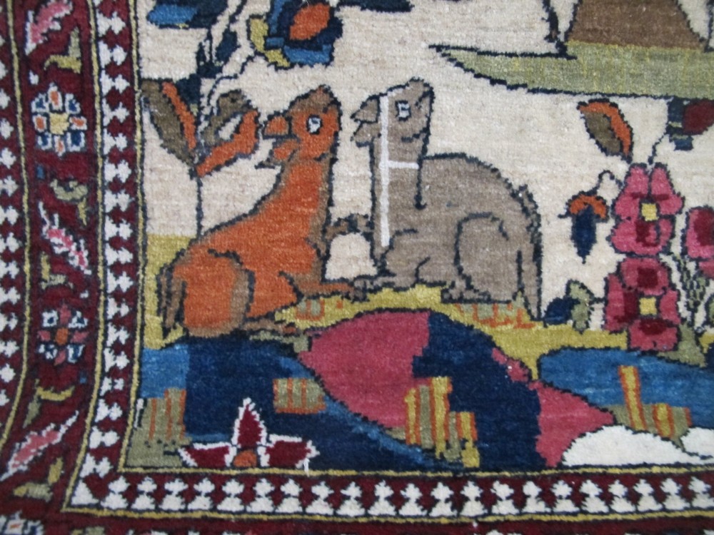 An antique hand-knotted Persian Isfahan wool rug featuring a central cream field with a detailed Tree of Life and bird motifs, framed by a wide deep red floral border. View IV