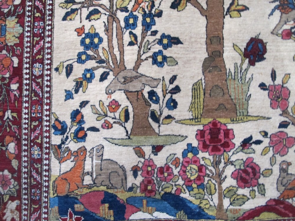 An antique hand-knotted Persian Isfahan wool rug featuring a central cream field with a detailed Tree of Life and bird motifs, framed by a wide deep red floral border. View VIII