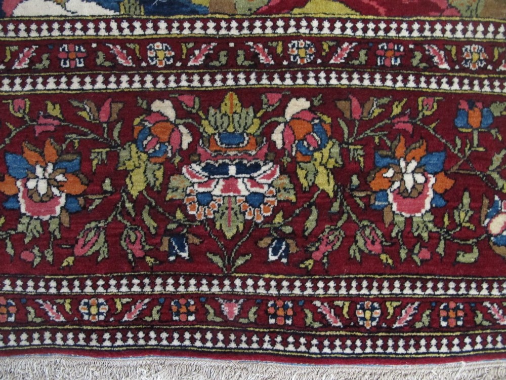 An antique hand-knotted Persian Isfahan wool rug featuring a central cream field with a detailed Tree of Life and bird motifs, framed by a wide deep red floral border. View X