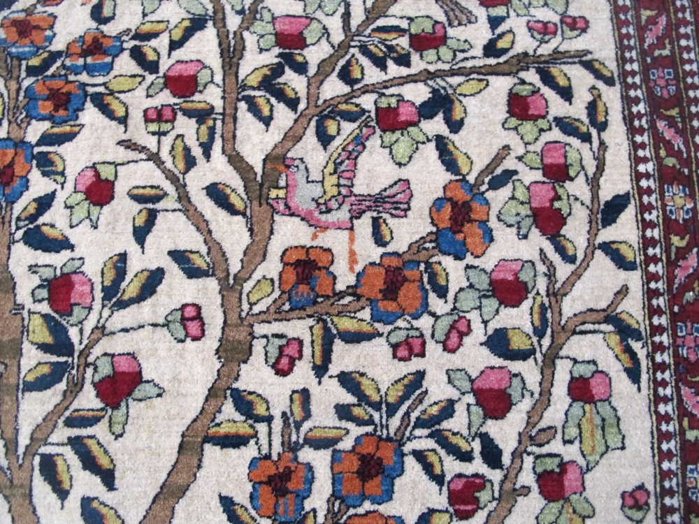 An antique hand-knotted Persian Isfahan wool rug featuring a central cream field with a detailed Tree of Life and bird motifs, framed by a wide deep red floral border. View XI
