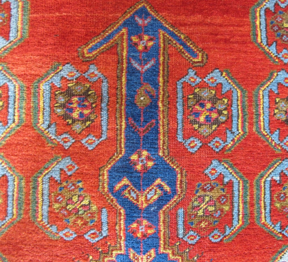 A long 19th-century Persian Bakshaish runner rug featuring central blue geometric diamond medallions on a bright red field with stylized floral borders. View VII