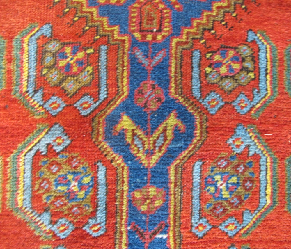 A long 19th-century Persian Bakshaish runner rug featuring central blue geometric diamond medallions on a bright red field with stylized floral borders. View VIII