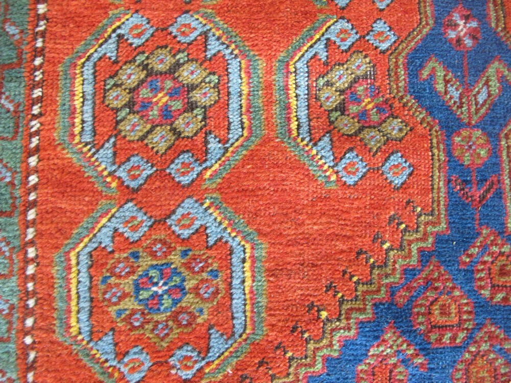 A long 19th-century Persian Bakshaish runner rug featuring central blue geometric diamond medallions on a bright red field with stylized floral borders. View XI