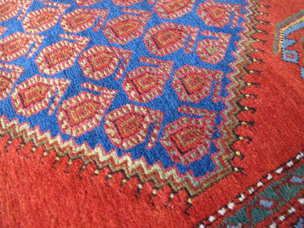 A long 19th-century Persian Bakshaish runner rug featuring central blue geometric diamond medallions on a bright red field with stylized floral borders. View XIII
