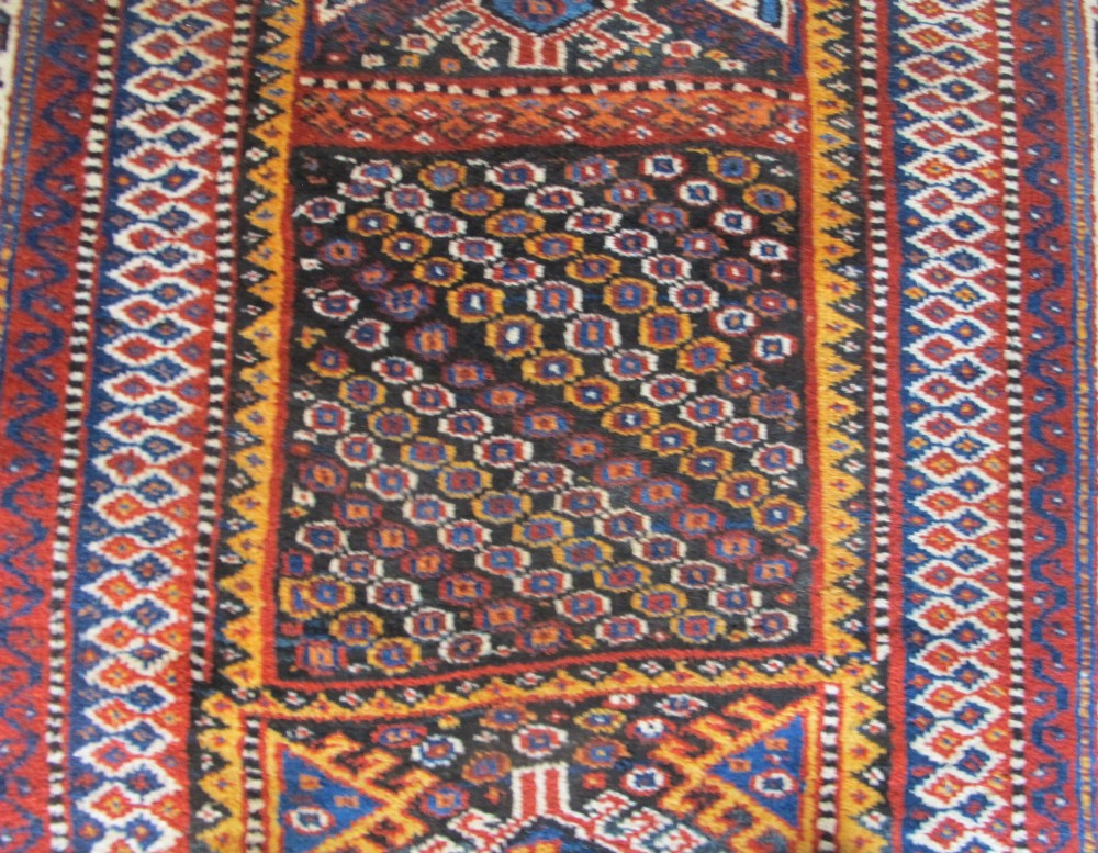 An antique late 19th-century Persian tribal runner rug with repeating geometric diamond medallions and layered borders in terracotta red, indigo blue, and ochre yellow. View IV
