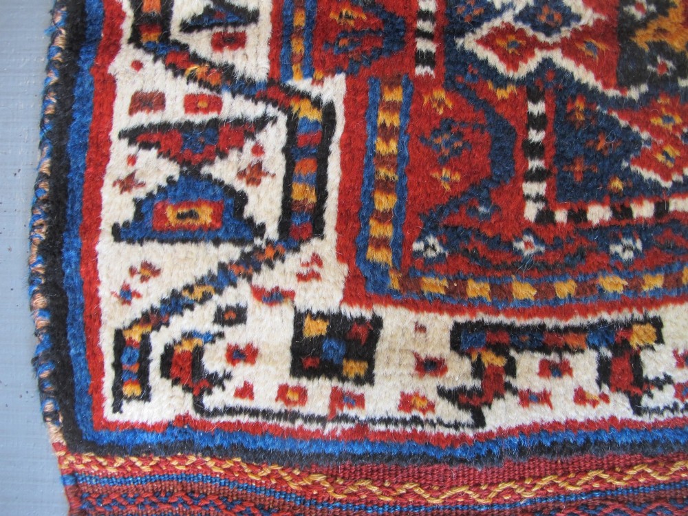 An antique late 19th-century Persian tribal runner rug with repeating geometric diamond medallions and layered borders in terracotta red, indigo blue, and ochre yellow. View VIII