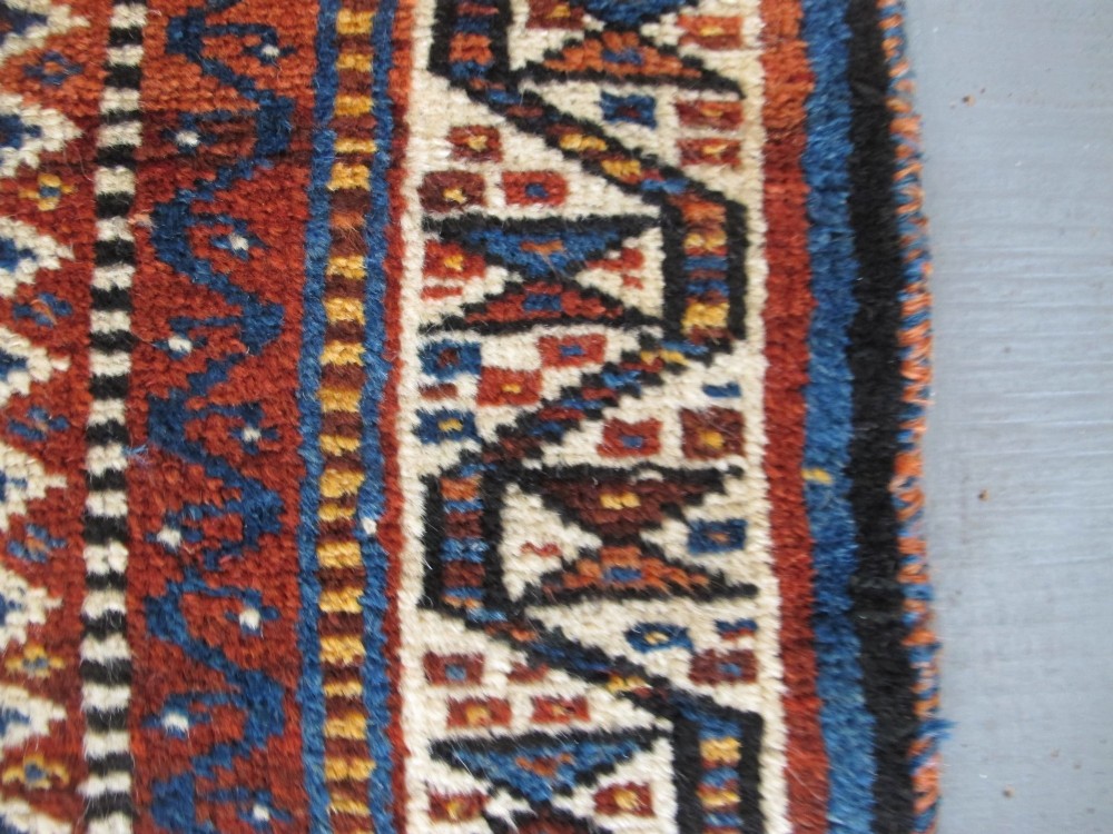 An antique late 19th-century Persian tribal runner rug with repeating geometric diamond medallions and layered borders in terracotta red, indigo blue, and ochre yellow. View XI