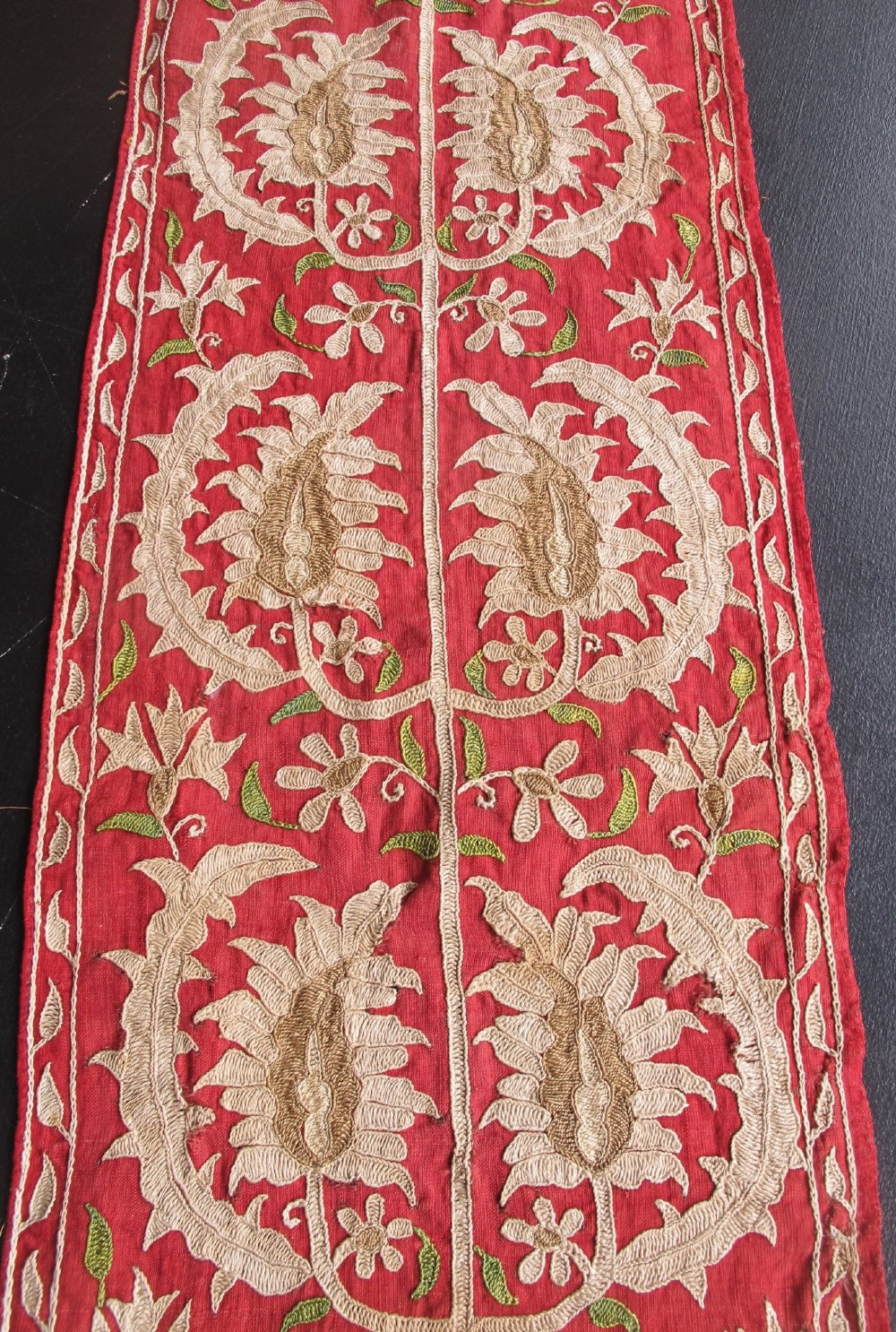 A long, narrow 19th-century Ottoman textile fragment featuring intricate gold botanical embroidery on a vibrant red background. View II