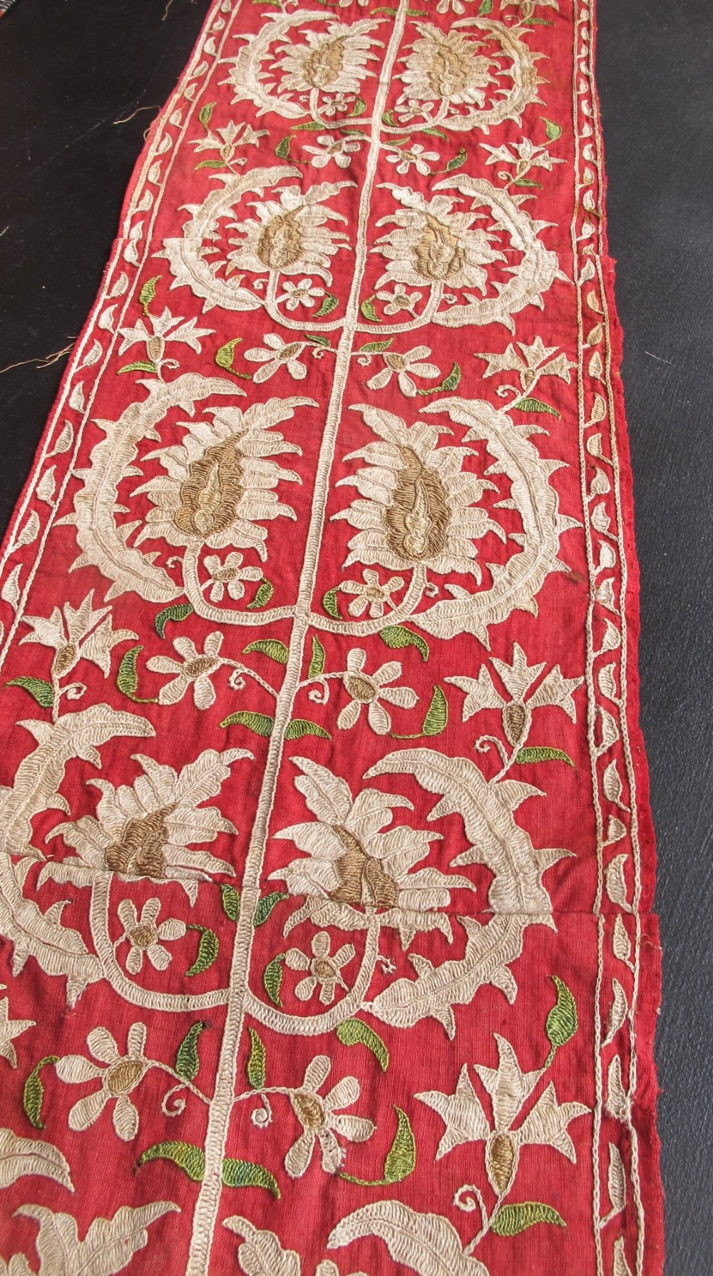A long, narrow 19th-century Ottoman textile fragment featuring intricate gold botanical embroidery on a vibrant red background. View X