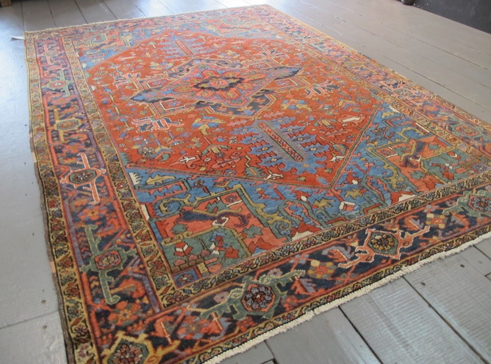 A hand-knotted late 19th-century Persian Heriz carpet featuring a central geometric medallion on a terracotta red field with blue spandrels and a multi-tiered border. View II