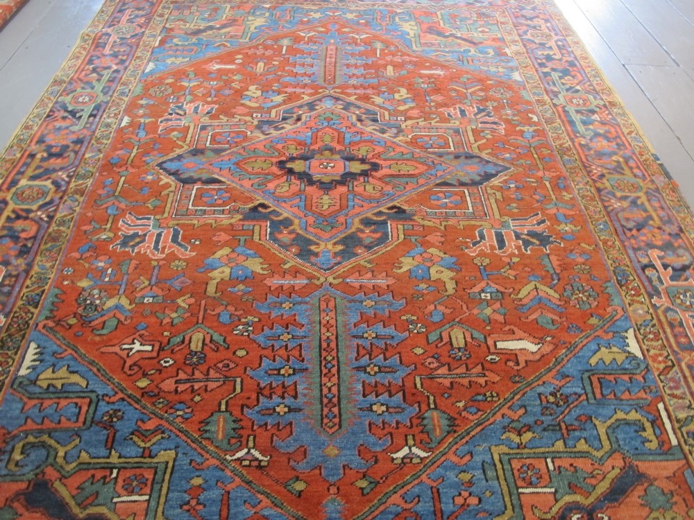 A hand-knotted late 19th-century Persian Heriz carpet featuring a central geometric medallion on a terracotta red field with blue spandrels and a multi-tiered border. View III