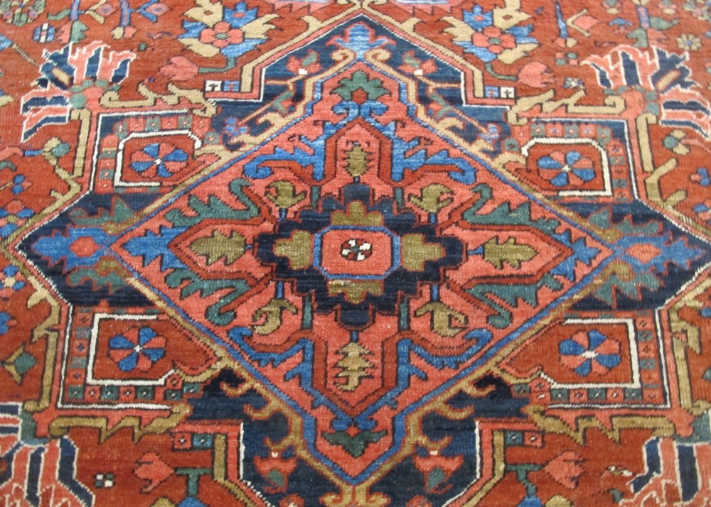 A hand-knotted late 19th-century Persian Heriz carpet featuring a central geometric medallion on a terracotta red field with blue spandrels and a multi-tiered border. View IV