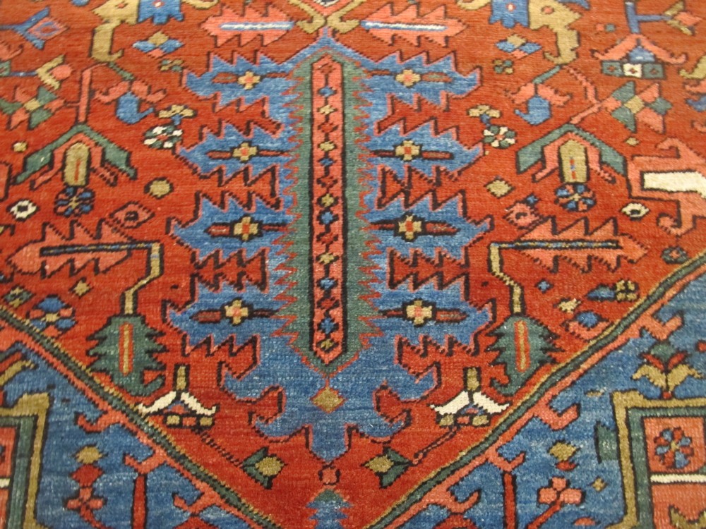 A hand-knotted late 19th-century Persian Heriz carpet featuring a central geometric medallion on a terracotta red field with blue spandrels and a multi-tiered border. View V