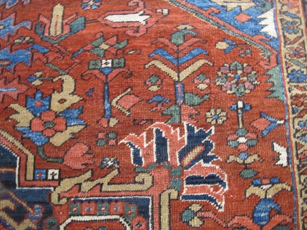 A hand-knotted late 19th-century Persian Heriz carpet featuring a central geometric medallion on a terracotta red field with blue spandrels and a multi-tiered border. View VIII