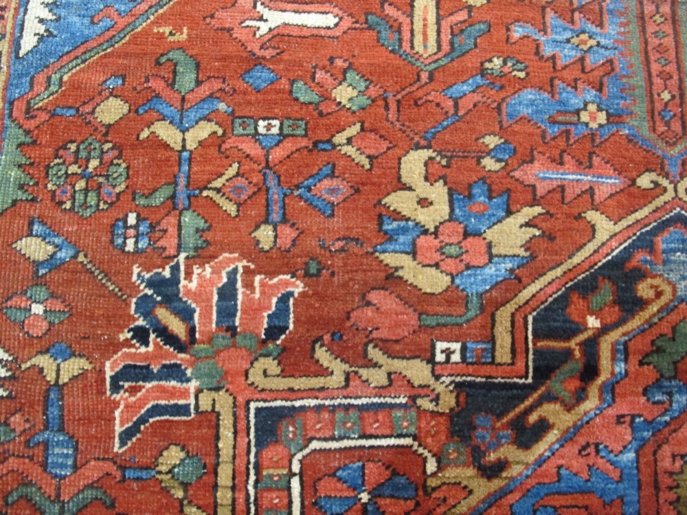A hand-knotted late 19th-century Persian Heriz carpet featuring a central geometric medallion on a terracotta red field with blue spandrels and a multi-tiered border. View IX