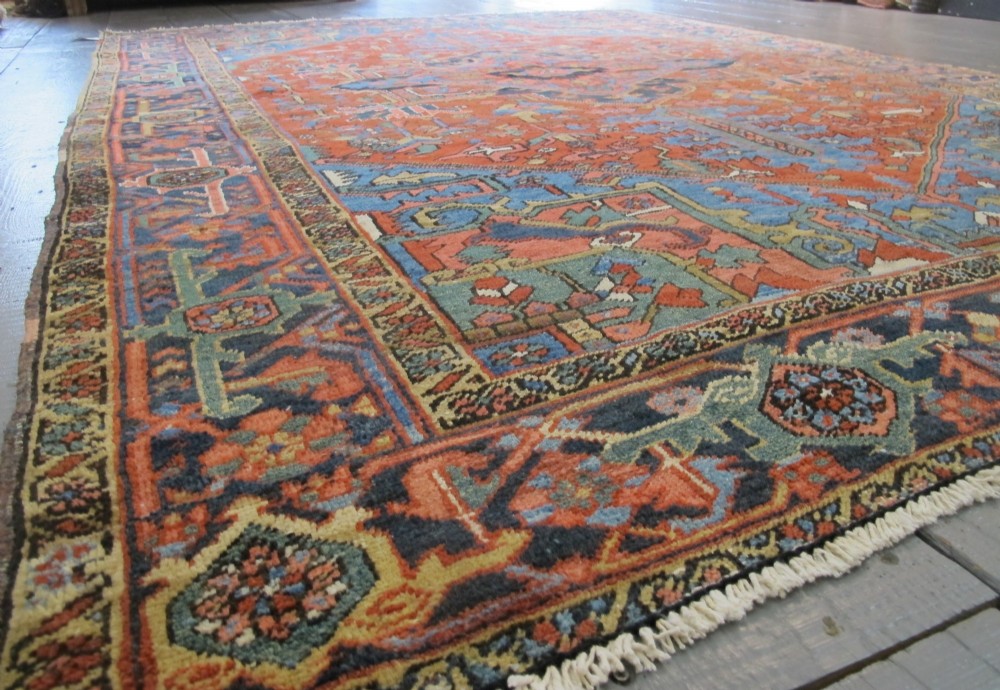 A hand-knotted late 19th-century Persian Heriz carpet featuring a central geometric medallion on a terracotta red field with blue spandrels and a multi-tiered border. View XI