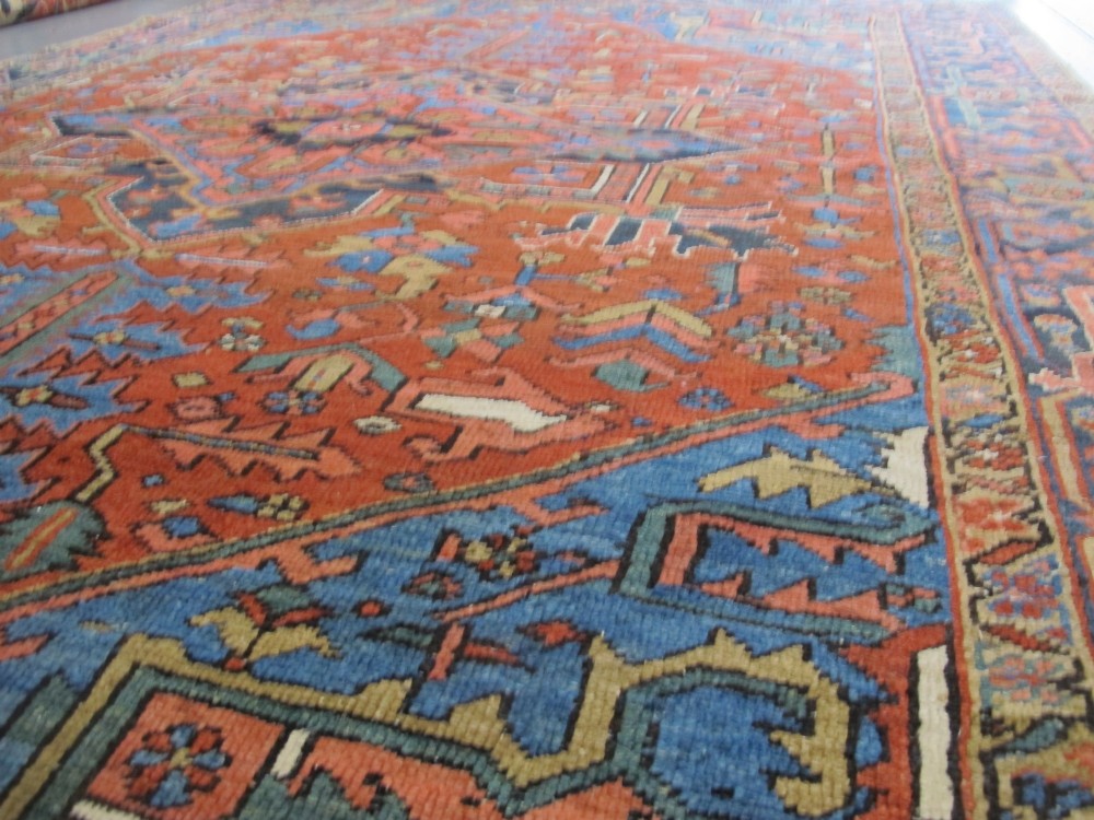 A hand-knotted late 19th-century Persian Heriz carpet featuring a central geometric medallion on a terracotta red field with blue spandrels and a multi-tiered border. View XII