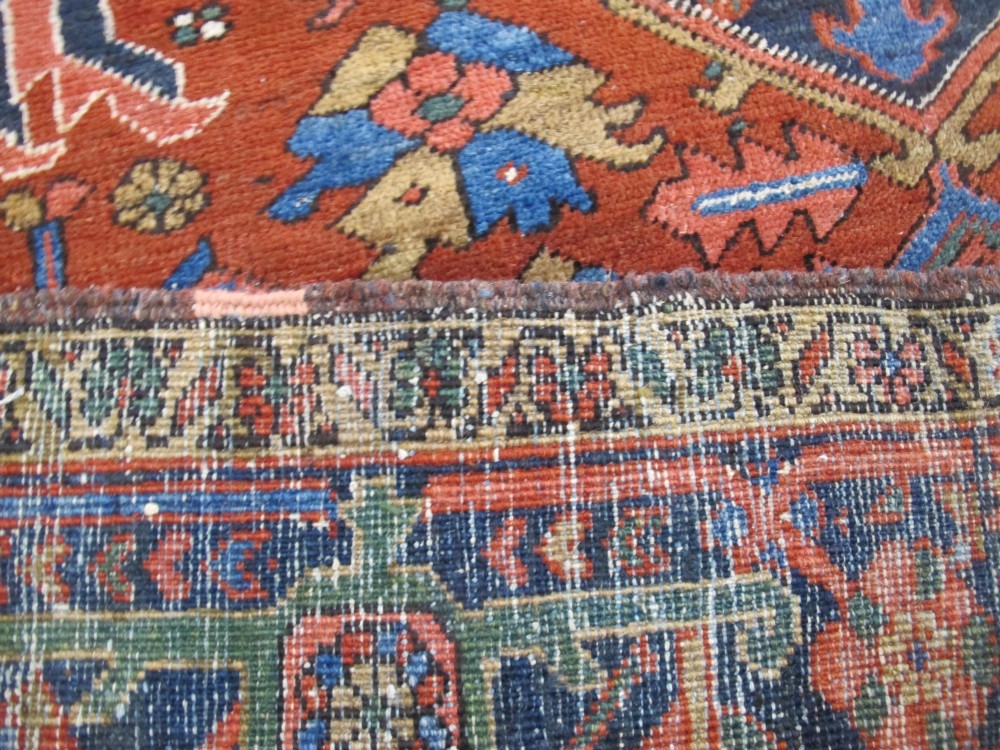A hand-knotted late 19th-century Persian Heriz carpet featuring a central geometric medallion on a terracotta red field with blue spandrels and a multi-tiered border. View XIII
