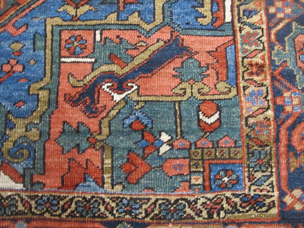 A hand-knotted late 19th-century Persian Heriz carpet featuring a central geometric medallion on a terracotta red field with blue spandrels and a multi-tiered border. View XIV