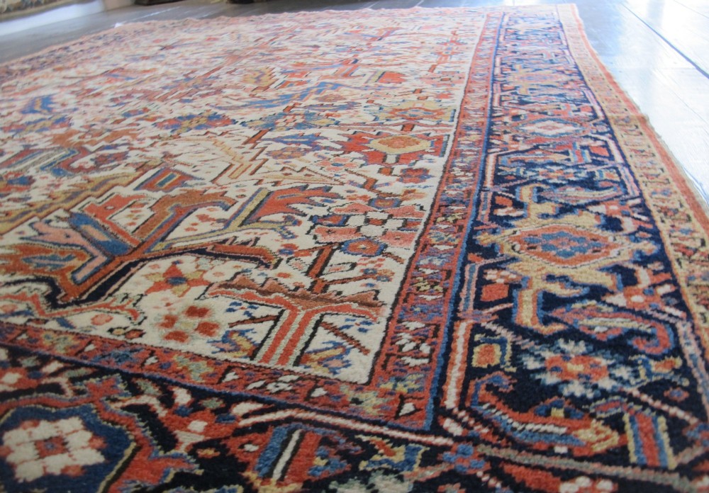 A large hand-knotted Persian Heriz rug featuring a central geometric medallion on an ivory background with terracotta and blue borders. View II