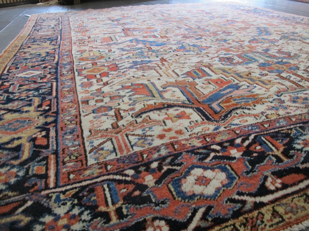 A large hand-knotted Persian Heriz rug featuring a central geometric medallion on an ivory background with terracotta and blue borders. View III