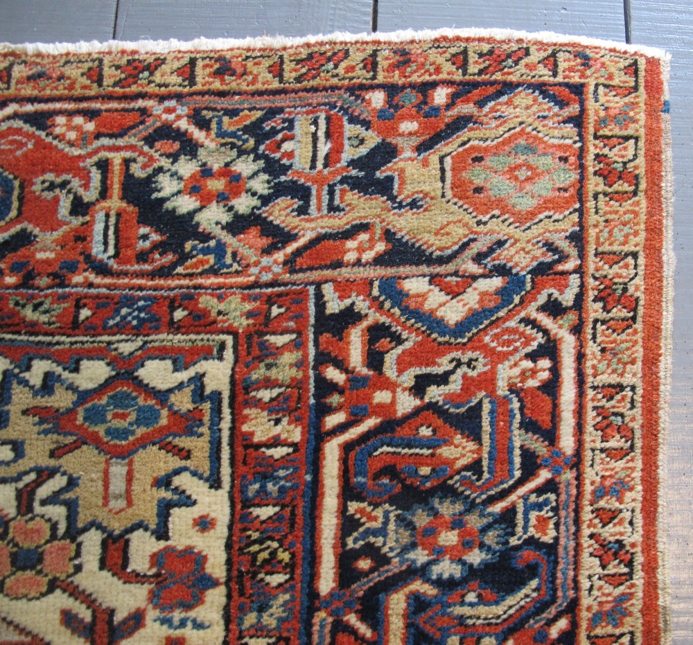 A large hand-knotted Persian Heriz rug featuring a central geometric medallion on an ivory background with terracotta and blue borders. View XI