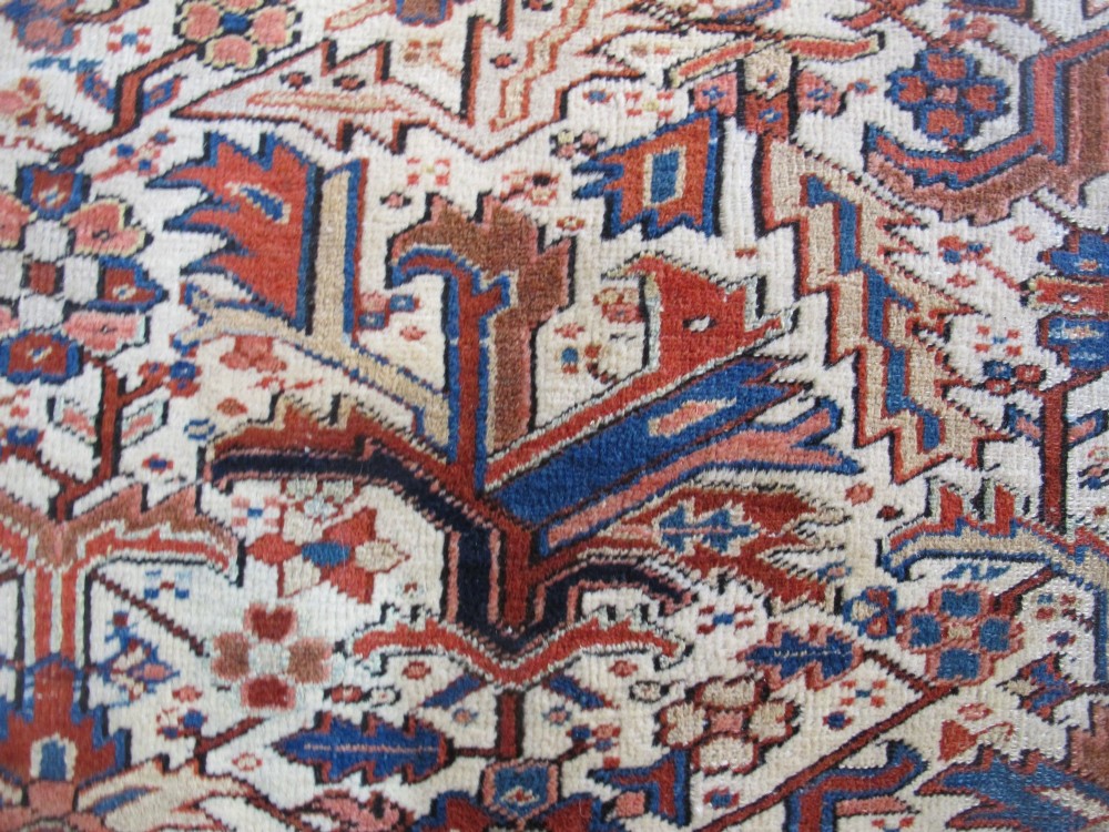 A large hand-knotted Persian Heriz rug featuring a central geometric medallion on an ivory background with terracotta and blue borders. View XII