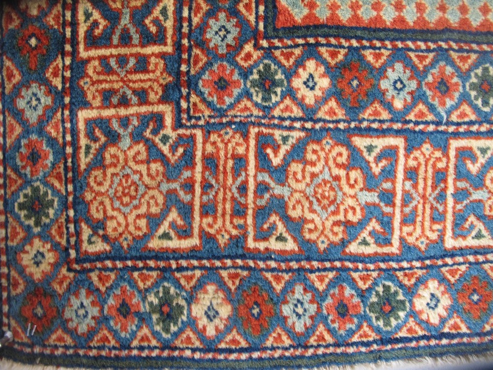 An antique Persian Tabriz wool rug featuring a light blue central field filled with repeating geometric floral motifs surrounded by multi-tiered terracotta and navy borders. View VI