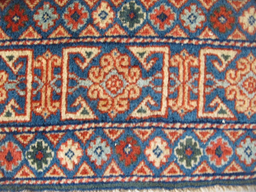 An antique Persian Tabriz wool rug featuring a light blue central field filled with repeating geometric floral motifs surrounded by multi-tiered terracotta and navy borders. View XI