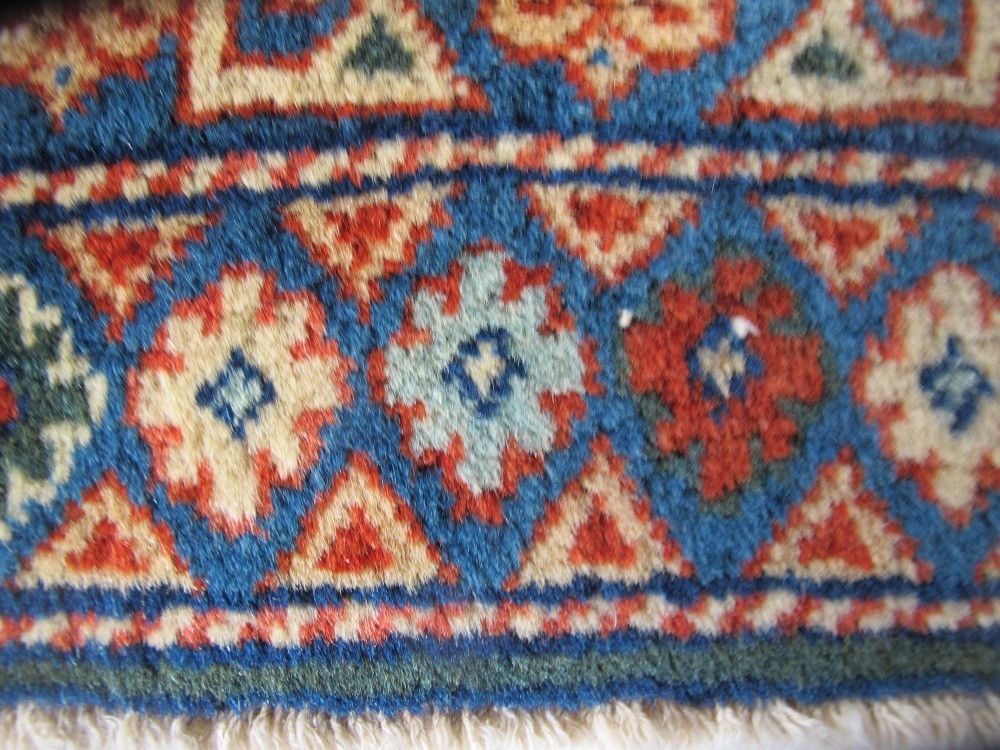 An antique Persian Tabriz wool rug featuring a light blue central field filled with repeating geometric floral motifs surrounded by multi-tiered terracotta and navy borders. View XII