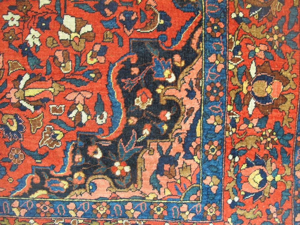 An antique Persian Bakhtiar hand-knotted wool rug featuring a central ivory and blue lobed medallion on a rich red field with floral motifs, surrounded by dark blue spandrels and borders. View V