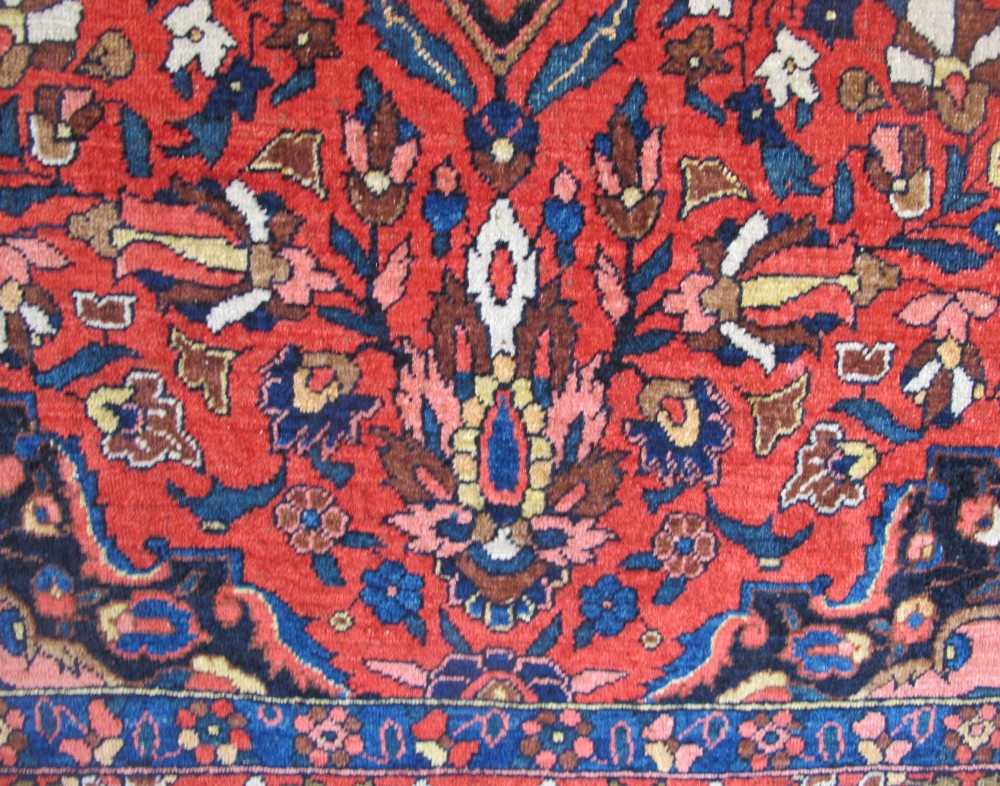 An antique Persian Bakhtiar hand-knotted wool rug featuring a central ivory and blue lobed medallion on a rich red field with floral motifs, surrounded by dark blue spandrels and borders. View VI