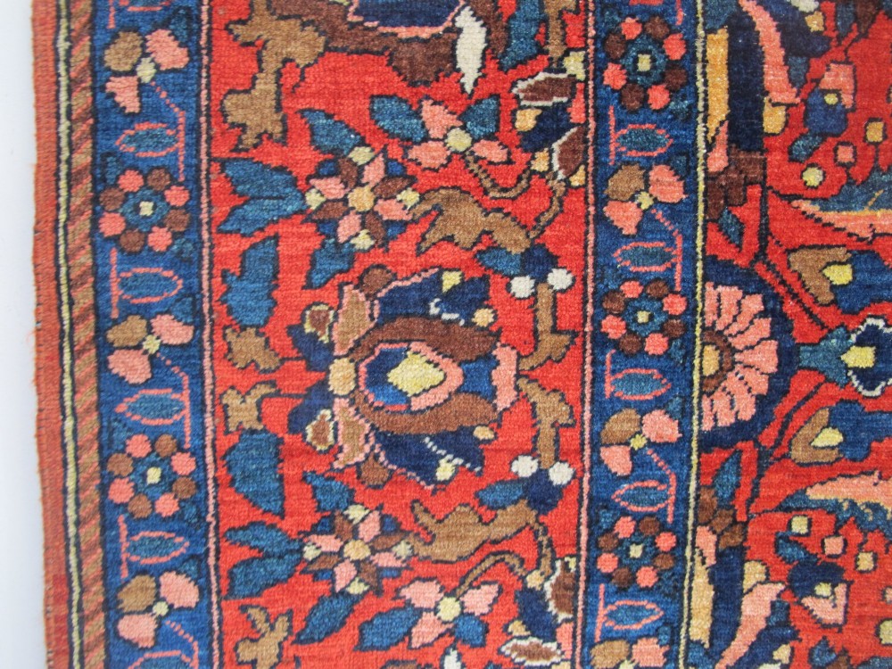 An antique Persian Bakhtiar hand-knotted wool rug featuring a central ivory and blue lobed medallion on a rich red field with floral motifs, surrounded by dark blue spandrels and borders. View VIII